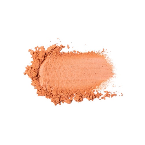 A smudge of crumbled powder blush on a white surface. The color is “Making Me Blush”, a warm peachy coral.